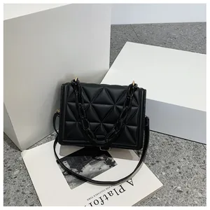 Detail of black quilted shoulder bag with acrylic chain and gold metal buckle