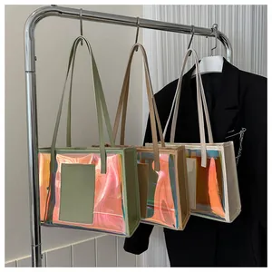 Three holographic laser PVC tote bags in green, caramel, and white hanging on a rack