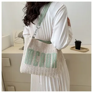Detail of woven straw tote bag with green leather strap and MCAOR lettering