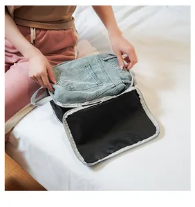 Black and grey travel organizer bag with mesh top showing jeans storage capacity