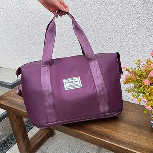 Detail view of purple waterproof travel bag showing reinforced handles and bottom compartment