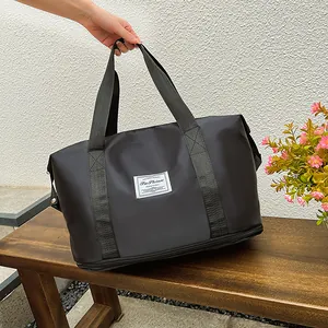 Detail view of black travel bag showing waterproof nylon texture and bottom zipper compartment