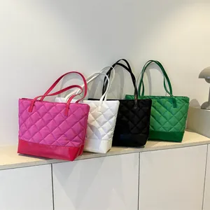 Diamond quilted tote bags in four colors arranged diagonally in a minimalist interior