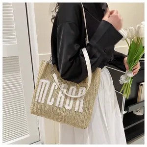 Detail of a large straw tote bag with MCROR embroidery and silver chain strap