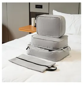 Stack of 4 grey compression packing cubes on a hotel bed for travel organization