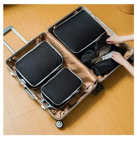 Detail of black nylon packing cubes organizing clothes and shoes inside a suitcase