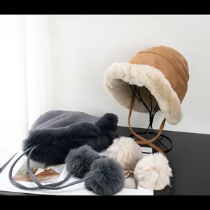 Detail showing plush winter bucket hat with faux fur trim and long pom-pom drawstrings