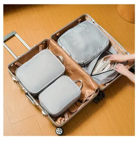 Detail view of grey packing cubes and a dedicated shoe bag inside an open silver suitcase