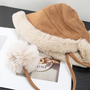 Detailed view of camel faux fur trapper hat with soft plush lining and pom-pom accent