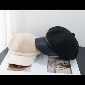 Close-up of retro newsboy caps in beige and black on an art magazine with soft lighting