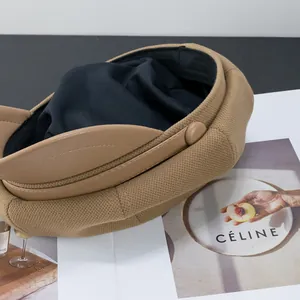 Close-up of khaki newsboy hat showing textured knit fabric and faux leather brim detail