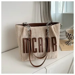 Detail of straw tote bag with brown leather straps and silver chain link accents