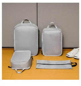 Detail of 4-piece light gray travel compression organizers on a light wood floor