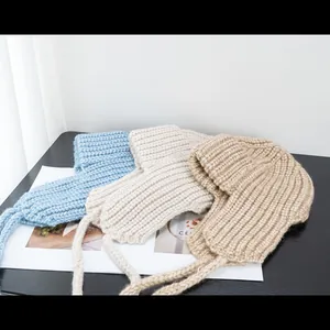 Close-up of thick ribbed knit balaclava hats in blue, white, and khaki with long ties
