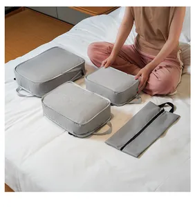 Detailed set of grey compression travel organizers on bed for luggage packing