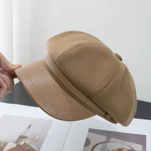 Close-up of brown newsboy hat featuring textured fabric and faux leather brim detail