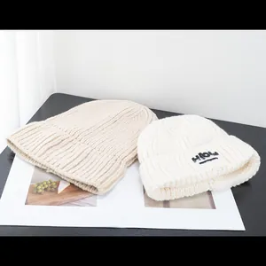 Gestrickte Beanie-Mütze in Beige und Cremeweiß mit HIOW-Logo für den Winter