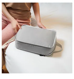 Gray travel organizer bag with handle being packed on a bed in a home setting