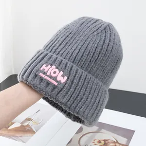 Detailaufnahme der grauen Strickmütze mit auffälligem rosa 'HioW' Stickerei-Aufnäher