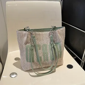 Straw tote bag with green leather trim and MCADE embroidery on a minimalist chair
