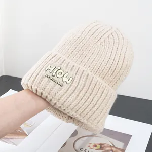 Detailaufnahme der beigen Strickmütze mit geripptem Design und modischem Logo-Patch