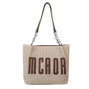 Large straw bucket bag with brown leather handles and MCAOR letter logo detail