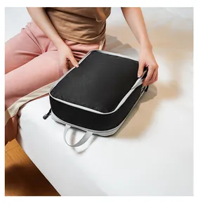 Woman holding a gray travel compression packing cube showing its portable size and handle