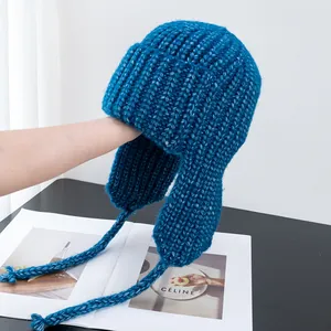 Detail of lake blue thick cable knit trapper hat with ear flaps and woven drawstrings