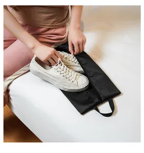 Detail of black mesh shoe travel bag with zipper and handle holding white sneakers