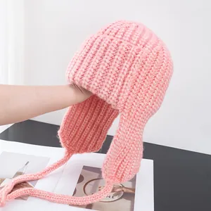 Detail showing soft pink knit texture and braided earflaps on winter beanie