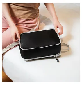 Detail of black compression packing cube with diamond texture and grey handle for travel