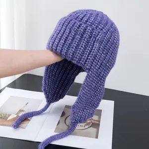Detail of purple chunky knit trapper hat showing soft texture and long straps