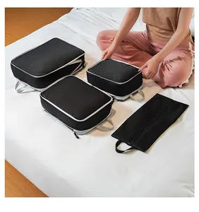 Detailed view of four-piece black travel organizer set with mesh panels on a bed