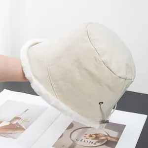 Detail of beige bucket hat showing faux fur trim and adjustable side drawstring toggle