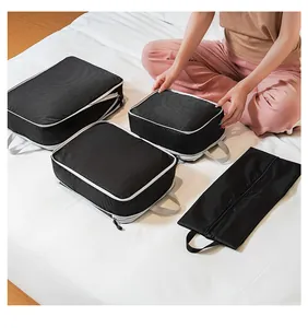 Detail of four-piece black compression packing cubes with white zippers on a bed