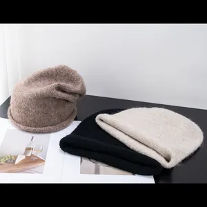 Bonnets en tricot d'alpaga en chameau noir et blanc cassé sur une surface texturée