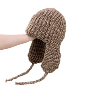 Brown chunky knit trapper hat with ear flaps and braided ties for winter warmth