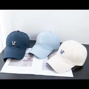 Navy, light blue and cream cotton baseball caps with U' HOPE embroidery on a black table