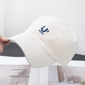 Close-up of embroidered HOPE text and smiley face on cream cotton baseball cap