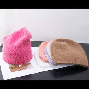 Dettaglio di berretti in maglia di pelo di coniglio in rosa, viola e crema