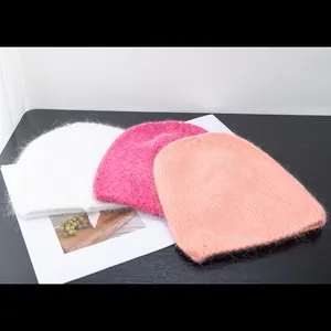 Posa piatta di berretti in maglia morbida in bianco, fucsia e rosa con soffice pelo di coniglio
