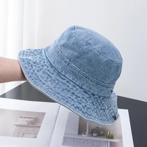 Détail d'un bob en denim bleu clair avec œillets métalliques et coutures renforcées au bord