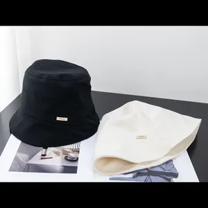 Detail showing checkered texture and leather brand label on bucket hats in black and beige