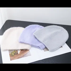 Dettaglio ravvicinato di berretti in maglia morbida nei colori crema, lavanda e grigio