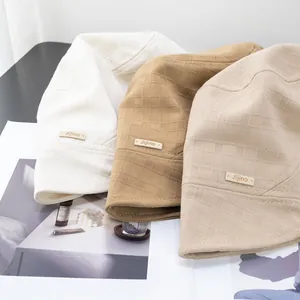 Detailed view of checkered cotton bucket hats with leather Jijino label on a magazine