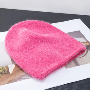 Dettaglio del berretto in maglia di mohair fucsia soffice appoggiato su una rivista