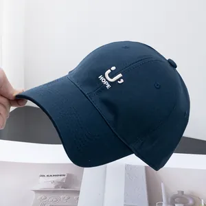 Detailed view of the U HOPE white embroidery on a navy blue cotton twill baseball cap