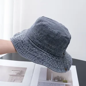 Détail d'un bob en jean délavé gris montrant les coutures et les œillets en bronze