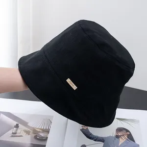 Detail of black cotton bucket hat showing fine plaid texture and Jijino side label