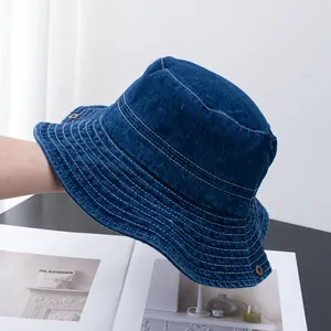 Détail d'un bob en jean bleu foncé avec surpiqûres blanches contrastées et boucle en métal vintage